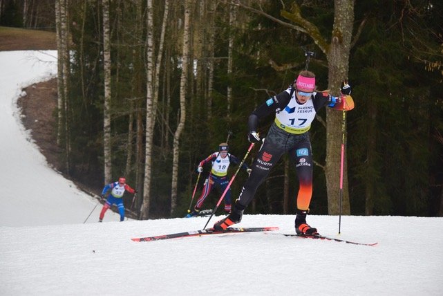 Biathlet im Wettkampf läuft mit Skiern und Gewehr auf dem Rücken