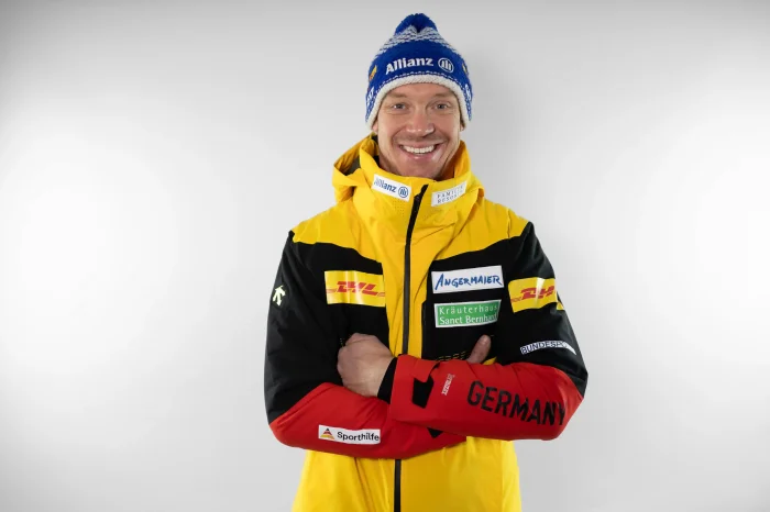 Sportler Felix Angermaier lächelt in gelber Germany Jacke mit blauer Mütze